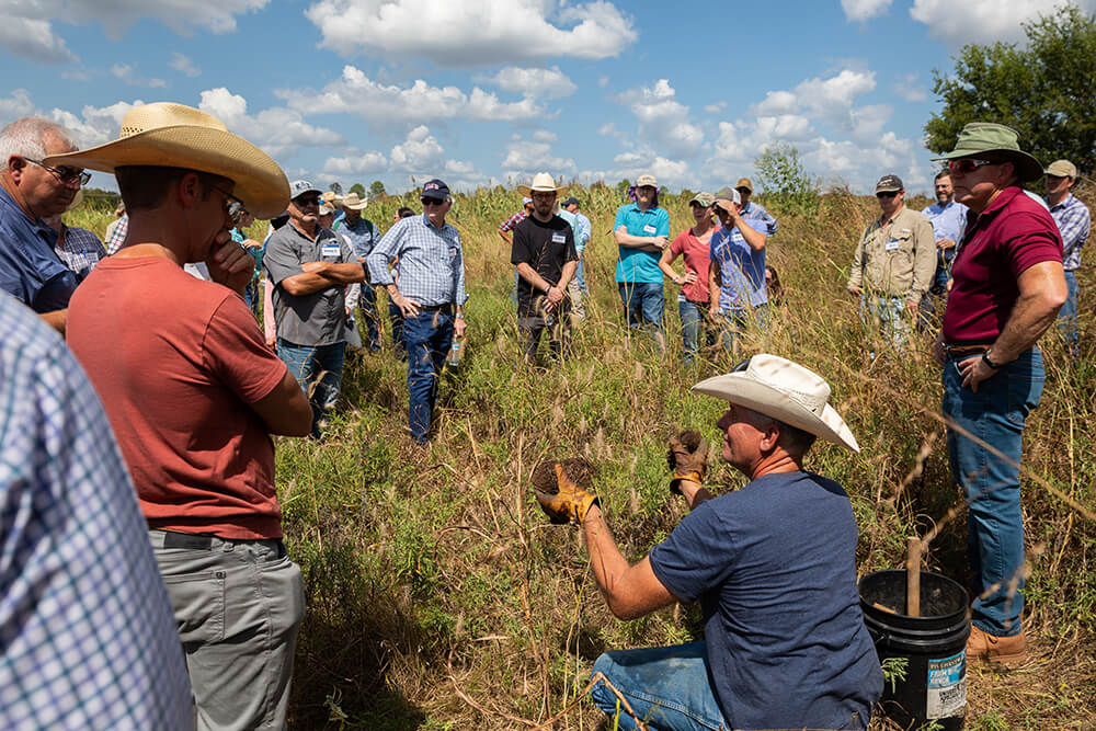 A group of ranchers visiting one of Noble's ranches examine soil samples taken from the ranch.