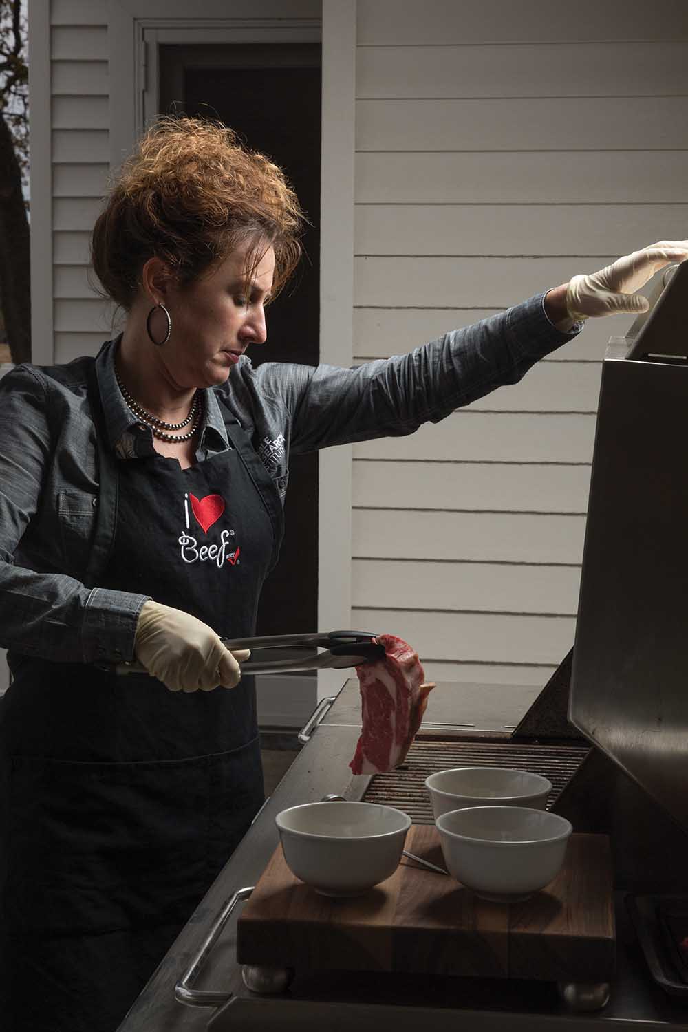 Becca McMillan marinates and places steak on a grill